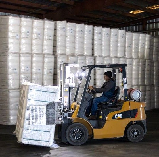 man driving forklift with bale of cotton